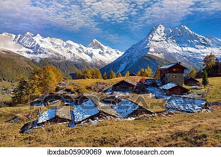 Stock Photo - Alpine huts in Val d'Hérens, behind them snow-covered Valais Alps, Canton Valais, Switzerland, Europe. Fotosearch