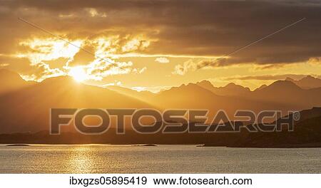 Stock Photo - Atmospheric sunset over a high mountain range, in front sea, Bodø, Nordland, Norway, Europe. Fotosearch