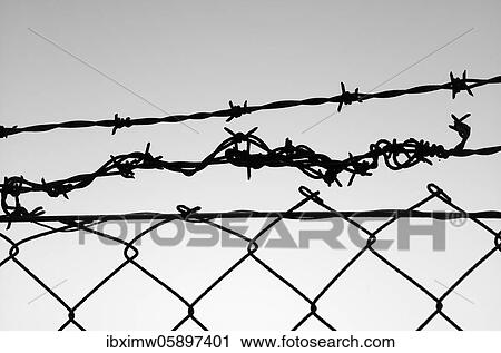 Stock Image - Barbed wire fence in front of the sky, symbolic picture of captivity, Stuttgart, Baden-Württemberg, Germany, Europe. Fotosearch