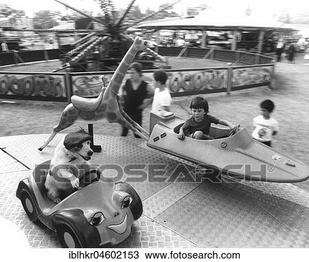 Stock Image - Boy and Jack Russell ride a carousel, England, Great Britain. Fotosearch