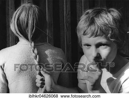 Stock Photo - Boy pulls girls by the hair about 1970s, exact place unknown, Czech Republic, Europe. Fotosearch