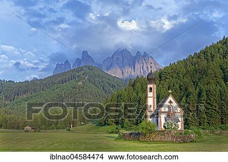 Picture - Church of St. Johann with cloudy Geislerspitzen in the background, Ranui, Villnößtal, South Tyrol, Italy, Europe. Fotosearch