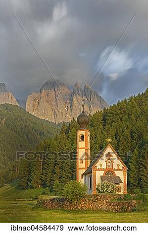 Stock Photo - Church of St. Johann with cloudy Geislerspitzen in the background, Ranui, Villnößtal, South Tyrol, Italy, Europe. Fotosearch