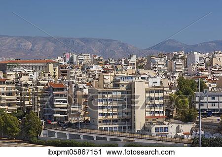 Stock Image - Commercial and residential buildings with mountain range in background, Piraeus, Athens region, Greece, Europe. Fotosearch