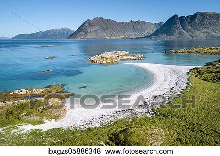 Stock Photo - Crescent-shaped bay, white sandy beach, turquoise sea, grassy coast in front, steep mountains behind, Vågan, Lofoten, Nordland, Norway, Europe. Fotosearch
