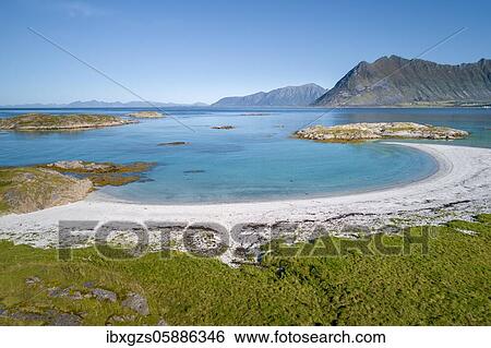 Stock Photograph - Crescent-shaped bay, white sandy beach, turquoise sea, grassy coast in front, steep mountains behind, Vågan, Lofoten, Nordland, Norway, Europe. Fotosearch