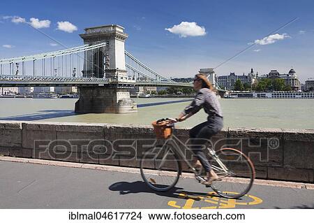 Cyclist on the bank of the Danube with Széchenyi Chain Bridge, view to Pest, Budapest, Hungary, Europe View Large Photo Image Picture - Cyclist on the bank of the Danube with Széchenyi Chain Bridge, view to Pest, Budapest, Hungary, Europe. Fotosearch