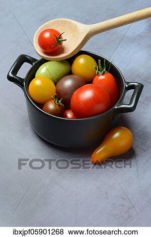 Stock Photo - Different cherry tomatoes in pot with cooking spoon, Germany, Europe. Fotosearch