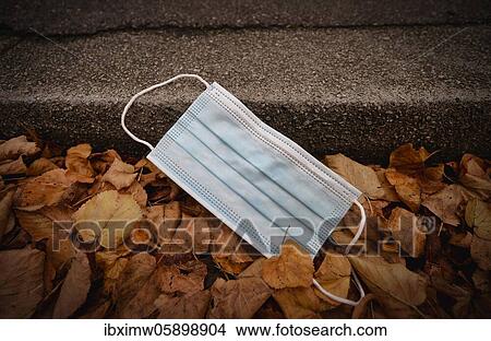 Picture - Discarded face mask lying on the ground in autumn foliage, corona crisis, Stuttgart, Baden-Württemberg, Germany, Europe. Fotosearch