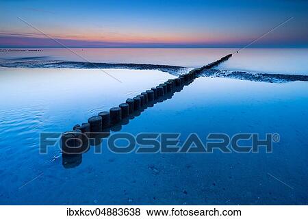 Stock Photo - Dusk at the beach of the Baltic Sea, groyne crosses sandbank, near Graal-Müritz, Mecklenburg-Western Pomerania, Germany, Europe. Fotosearch