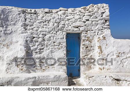 Exposed white painted stone building wall with narrow blue painted front entrance door, Mykonos Town, Mykonos Island, Greece, Europe View Large Photo Image Stock Photo - Exposed white painted stone building wall with narrow blue painted front entrance door, Mykonos Town, Mykonos Island, Greece, Europe. Fotosearch