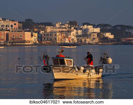 Stock Image - Fisherman early in the morning on his boat in the harbour, Ischia Ponte, Ischia, Calabria, Italy, Europe. Fotosearch