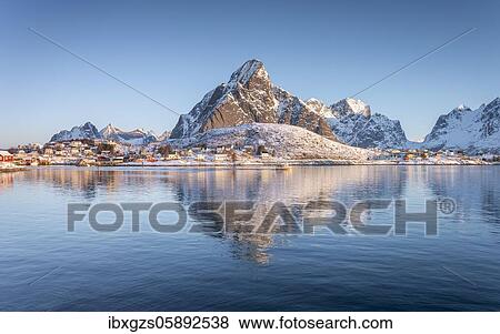 Stock Photo - Fishing village reflected in the sea, snowy mountains in the back, Reine, Nordland, Lofoten, Norway, Europe. Fotosearch