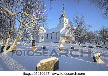 Stock Photo - Fore wooden church with snowy cemetery with gravestones, Reipå, Nordland, Norway, Europe. Fotosearch