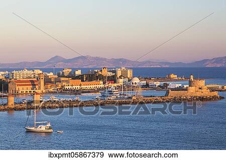 Stock Photo - Fort of Saint Nicholas with Mandraki marina at sunrise, Rhodes, Greece, Europe. Fotosearch