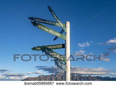 Stock Photo - Green signs, signposts with different destinations, Queenstown, South Island, New Zealand, Oceania. Fotosearch