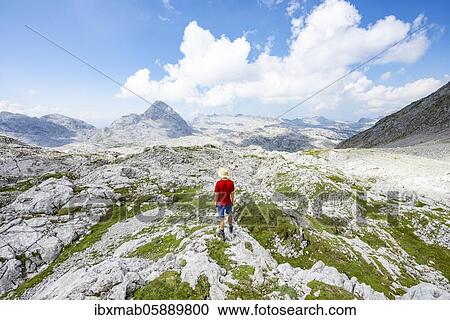 Stock Image - Hiker looks into the distance, landscape of washed out karst stone rocks, Funtenseetauern, Steinernes Meer, Berchtesgaden National Park, Berchtesgadener Land, Upper Bavaria, Bavaria, Germany, Europe. Fotosearch