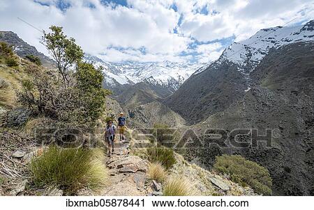 Stock Image - Hiker on a hiking trail, hiking trail Vereda de la Estrella, behind Sierra Nevada with summits Mulhacén and Pico Alcazaba, snow-covered mountains near Granada, Andalusia, Spain, Europe. Fotosearch