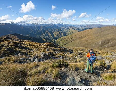 Stock Photo - Hiker photographed, hiking trail to Ben Lomond, view of mountains, Southern Alps, Otago, South Island, New Zealand, Oceania. Fotosearch