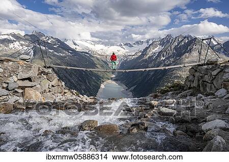 Hiker, woman on suspension bridge at the Olpererhütte, Schlegeis reservoir, Schlegeis reservoir, Zillertal Alps, Schlegeiskees glacier, Zillertal, Tyrol, Austria, Europe View Large Photo Image Picture - Hiker, woman on suspension bridge at the Olpererhütte, Schlegeis reservoir, Schlegeis reservoir, Zillertal Alps, Schlegeiskees glacier, Zillertal, Tyrol, Austria, Europe. Fotosearch