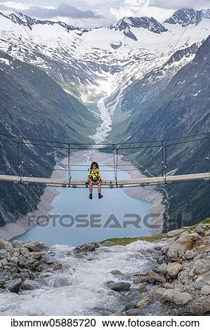Stock Image - Hiker, woman on suspension bridge at the Olpererhütte, Schlegeis reservoir, Schlegeis reservoir, Zillertal Alps, Schlegeiskees glacier, Zillertal, Tyrol, Austria, Europe. Fotosearch