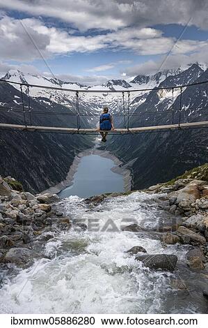 Stock Image - Hiker, woman on suspension bridge at the Olpererhütte, Schlegeis reservoir, Schlegeis reservoir, Zillertal Alps, Schlegeiskees glacier, Zillertal, Tyrol, Austria, Europe. Fotosearch