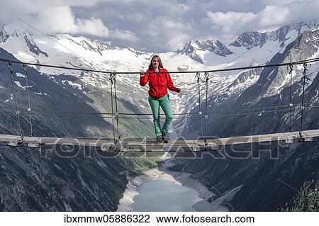 Stock Image - Hiker, woman on suspension bridge at the Olpererhütte, Schlegeis reservoir, Schlegeis reservoir, Zillertal Alps, Schlegeiskees glacier, Zillertal, Tyrol, Austria, Europe. Fotosearch