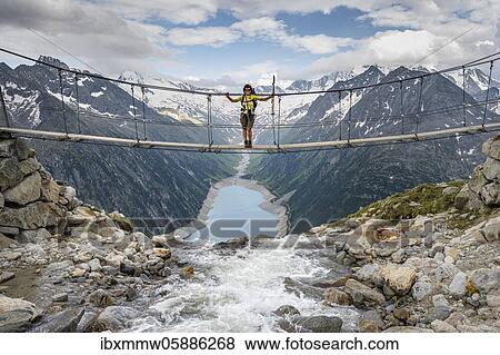 Hiker, woman on suspension bridge at the Olpererhütte, Schlegeis reservoir, Schlegeis reservoir, Zillertal Alps, Schlegeiskees glacier, Zillertal, Tyrol, Austria, Europe View Large Photo Image Stock Photo - Hiker, woman on suspension bridge at the Olpererhütte, Schlegeis reservoir, Schlegeis reservoir, Zillertal Alps, Schlegeiskees glacier, Zillertal, Tyrol, Austria, Europe. Fotosearch