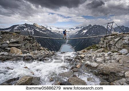 Hiker, woman on suspension bridge at the Olpererhütte, Schlegeis reservoir, Schlegeis reservoir, Zillertal Alps, Schlegeiskees glacier, Zillertal, Tyrol, Austria, Europe View Large Photo Image Stock Photo - Hiker, woman on suspension bridge at the Olpererhütte, Schlegeis reservoir, Schlegeis reservoir, Zillertal Alps, Schlegeiskees glacier, Zillertal, Tyrol, Austria, Europe. Fotosearch