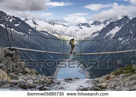 Stock Photography - Hiker, woman on suspension bridge at the Olpererhütte, Schlegeis reservoir, Schlegeis reservoir, Zillertal Alps, Schlegeiskees glacier, Zillertal, Tyrol, Austria, Europe. Fotosearch