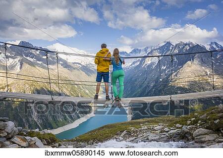 Hiker, young woman and young man on suspension bridge at the Olpererhütte, Schlegeis reservoir, Schlegeis reservoir, Zillertal Alps, Schlegeiskees glacier, Zillertal, Tyrol, Austria, Europe View Large Photo Image Stock Photography - Hiker, young woman and young man on suspension bridge at the Olpererhütte, Schlegeis reservoir, Schlegeis reservoir, Zillertal Alps, Schlegeiskees glacier, Zillertal, Tyrol, Austria, Europe. Fotosearch