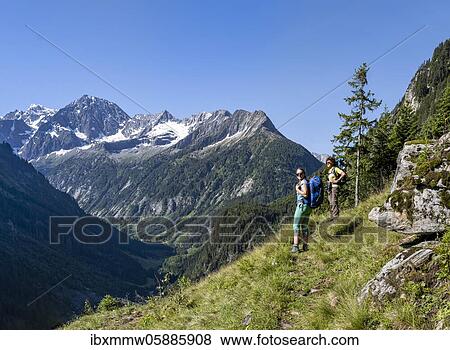 Stock Photo - Hikers look at mountains, Zamser Eck, Kleiner Hochsteller, Kälberlahnerspitze and Hochsteller, Zillertaler Alps, Zillertal, Tyrol, Austria, Europe. Fotosearch
