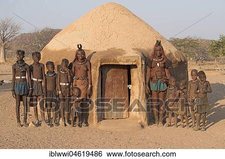 Stock Photograph - Himba women and children in front of a mud hut, Kaokoveld, Kunene, Namibia, Africa. Fotosearch
