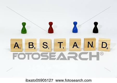Stock Photo - Letter blocks form the word "Abstand" (distance), behind them colourful game pieces, symbolic image of the distance rule in the Corona crisis, Germany, Europe. Fotosearch