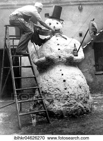 Stock Image - Man adorns big snowman, ca. 1955, Leipzig, Germany, Europe. Fotosearch