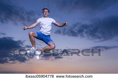Stock Photo - Man jumping, sunset, Germany, Europe. Fotosearch