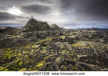 Man on a hill in a black lava field with green moss stretching hands into the dramatic sky, Leihrnjukur in the Krafla, Skútustaðir, Norðurland eystra, Iceland, Europe View Large Photo Image Stock Photo - Man on a hill in a black lava field with green moss stretching hands into the dramatic sky, Leihrnjukur in the Krafla, Skútustaðir, Norðurland eystra, Iceland, Europe. Fotosearch
