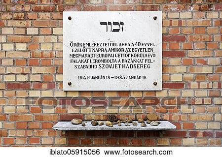 Stock Photograph - Memorial plaque commemorating the liberation of the Jewish ghetto on a wall of red bricks, with stones laid down on a marble slab underneath, Great Synagogue, Nagy Zsinagóga, Pest district, Budapest, Hungary, Europe. Fotosearch