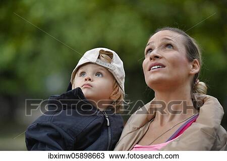 Stock Image - Mother holding son, 2 years old, in her arms, looking up, Stuttgart Baden-Württemberg, Germany, Europe. Fotosearch