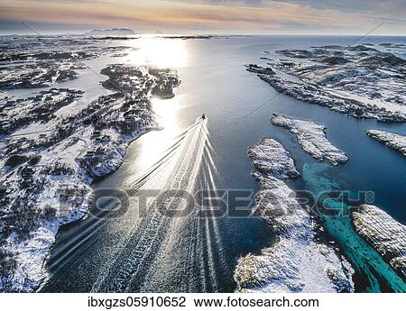 Stock Image - Motorboat sailing through a winter fjord landscape with small islands, Herøy, Nordland, Norway, Europe. Fotosearch