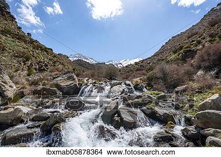 Picture - Mountain stream Rio Valdeinfierno, hiking trail near Junta de los Rios, behind Sierra Nevada with summits Mulhacén and La Alcazaba, snow-covered mountains near Granada, Andalusia, Spain, Europe. Fotosearch
