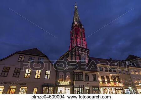 Picture - Neo-Gothic Nicolai church, colorful illuminated around Christmas time, in front of old town houses, Lüneburg, Lower Saxony, Germany, Europe. Fotosearch