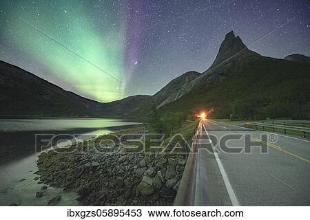 Stock Image - Night shot of (Aurora borealis) a road with illuminated entrance to the tunnel, starry sky, northern lights Northern Lights, in the back mountain top Stetind, Stetinden, Nordland, Norway, Europe. Fotosearch