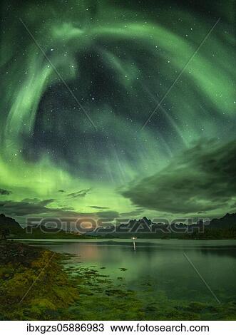 Stock Image - Northern lights over the fjord, behind them rugged peaks of the mountain range Trolltindan, Digermulen, Nordland, Lofoten, Norway, Europe. Fotosearch