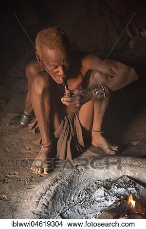Picture - Old Himba chief sitting at the fire in his hut, Kaokoveld, Namibia, Africa. Fotosearch