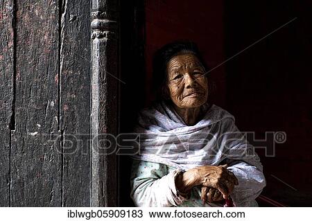 Stock Image - Portrait of an older woman looking out of a doorway, Patan, Lalitpur, Kathmandu, Nepal, Asia. Fotosearch