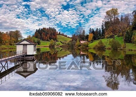 Stock Image - Reflection of the hilly landscape with autumn coloured trees in the Wenigerweier, St. Gallen, Canton St. Gallen, Switzerland, Europe. Fotosearch