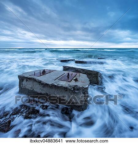 Stock Image - Remains of a bunker in the surf of the Baltic Sea below the steep coast at stormy sea, high shore, seaside resort Wustrow, peninsula Fischland-Darß-Zingst, National Park Vorpommersche Boddenlandschaft, Mecklenburg-Vorpommern, Germany, Europe. Fotosearch