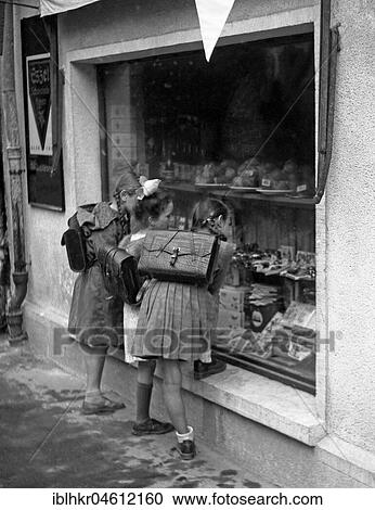 Stock Image - School children are standing in front of a shop window, Freiburg approx. 1945 to 1955. Fotosearch
