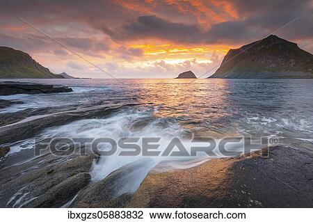 Stock Image - Sea surf in warm evening light with coastal landscape on Lofoten, Haukland Strand, Vestvågøy, Lofoten, Nordland, Norway, Europe. Fotosearch